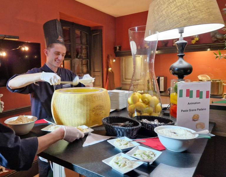 Chef préparant un plat de pâtes dans une meule de parmesan géante pour événement thème trattoria italienne par Lecointe Stories, organisateur d'événements en Normandie