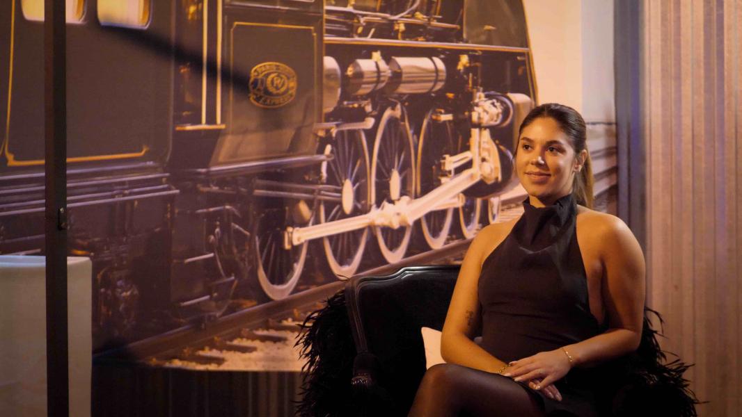 Femme devant une grande toile représentant un train pour événement thème Paris-Venise Express par Lecointe Stories, organisateur d'événements en Normandie